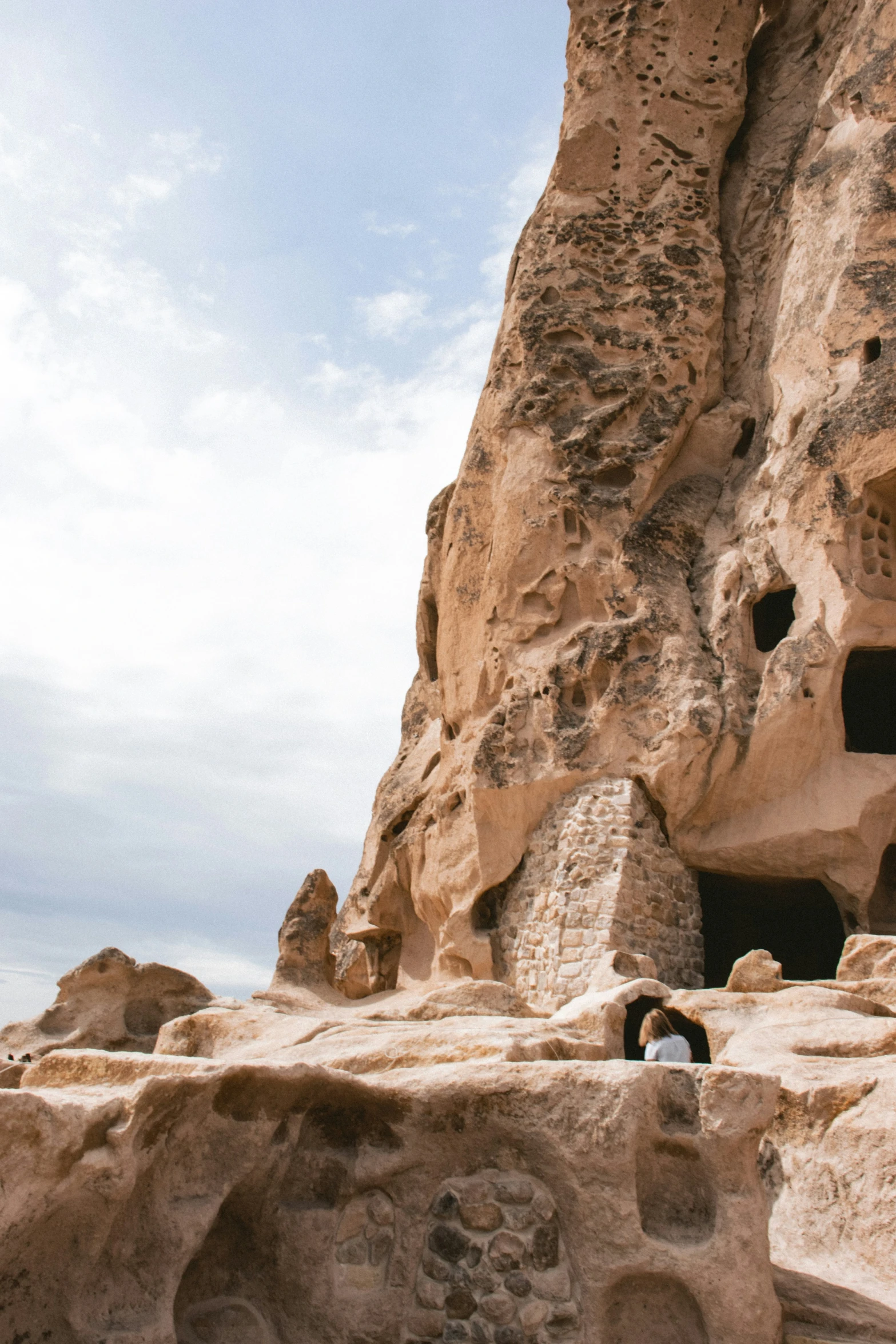 a man sits by a rock formation with a tunnel