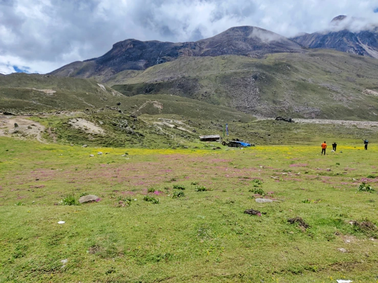 two people walking across the grass with mountains in the background