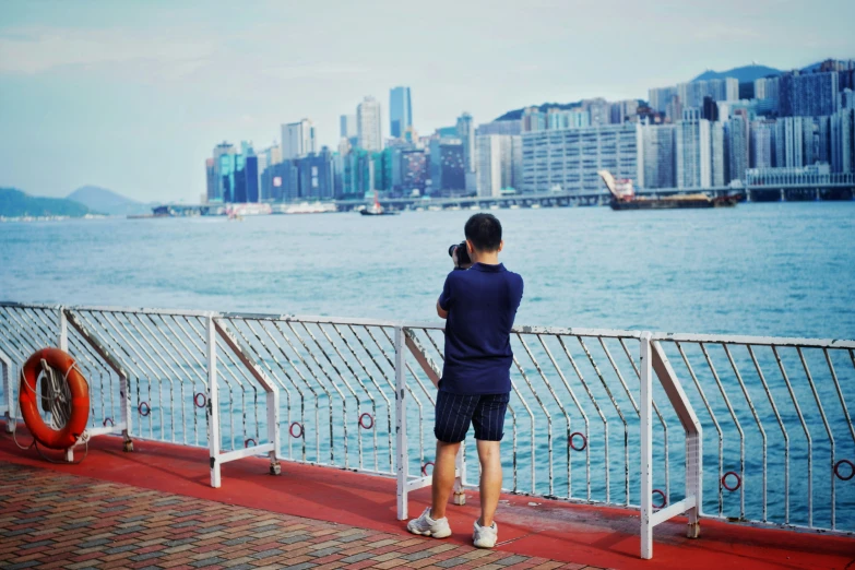 a man standing on the edge of a pier looking out at the water