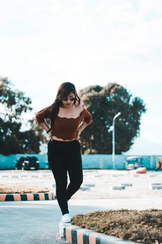 the woman wearing a crop top and pants runs on the curb