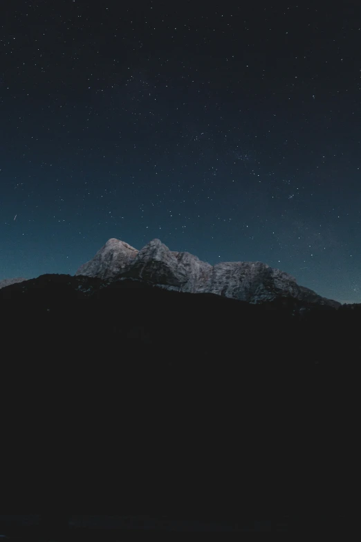 the night sky above a mountain range with stars above