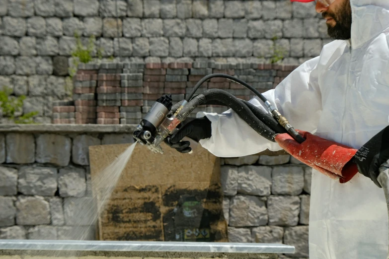 a worker in protective clothing spraying the outside of a wall
