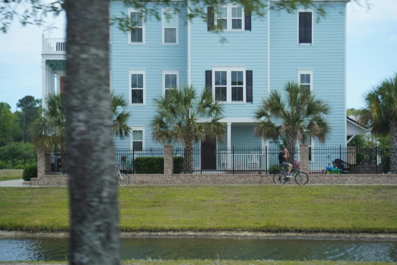 a man riding a bike past a blue apartment