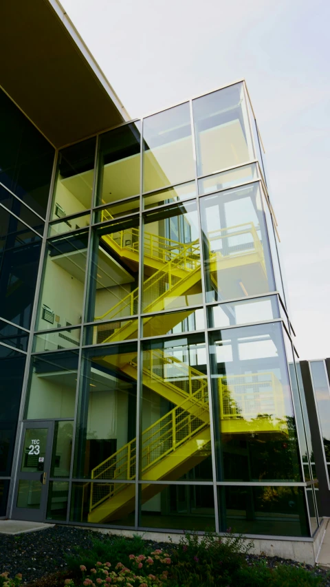 a modern glass building with a set of yellow staircases on each level