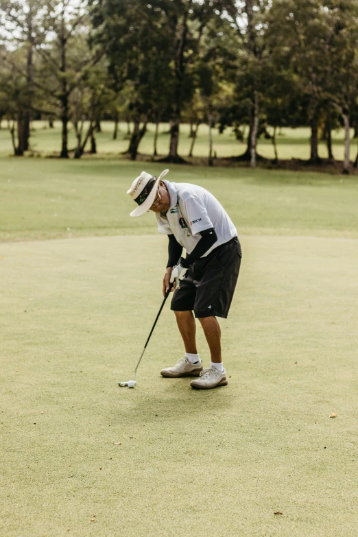 a man in a golf uniform putting the ball into his tee