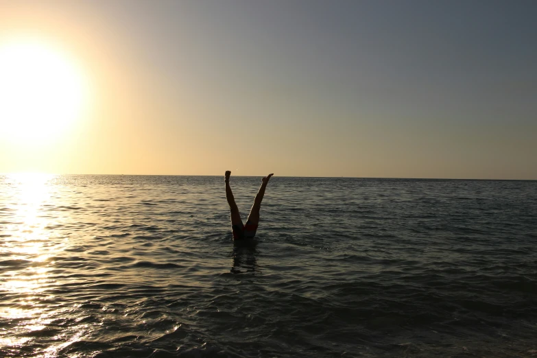 someone standing in the middle of the ocean near the sun