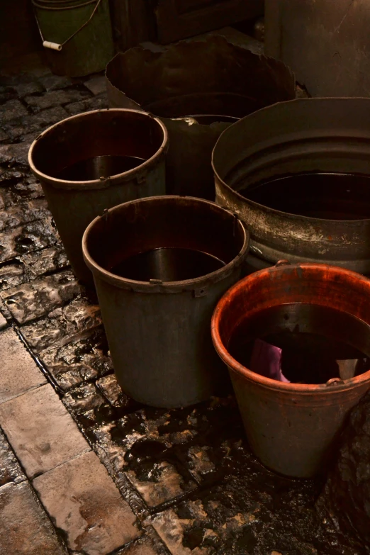 three pots and an orange container on a tile floor