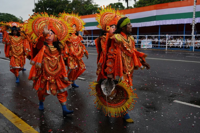 a group of young people dressed in red and gold performing in the street