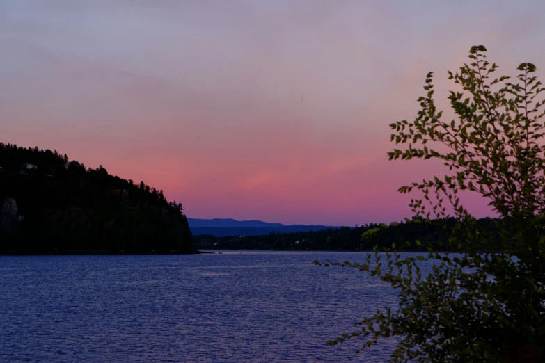 the sunset is going on in the pink clouds over the water