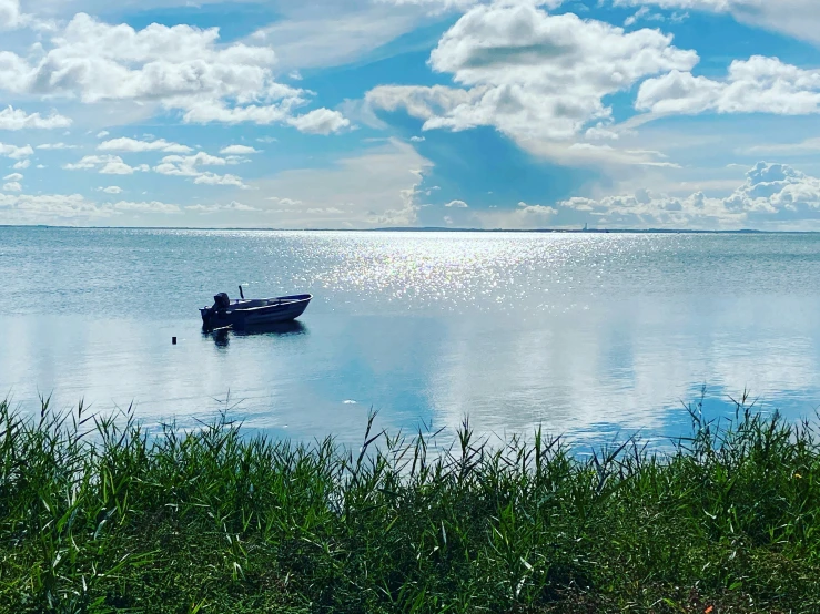 a boat traveling across a lake surrounded by green grass