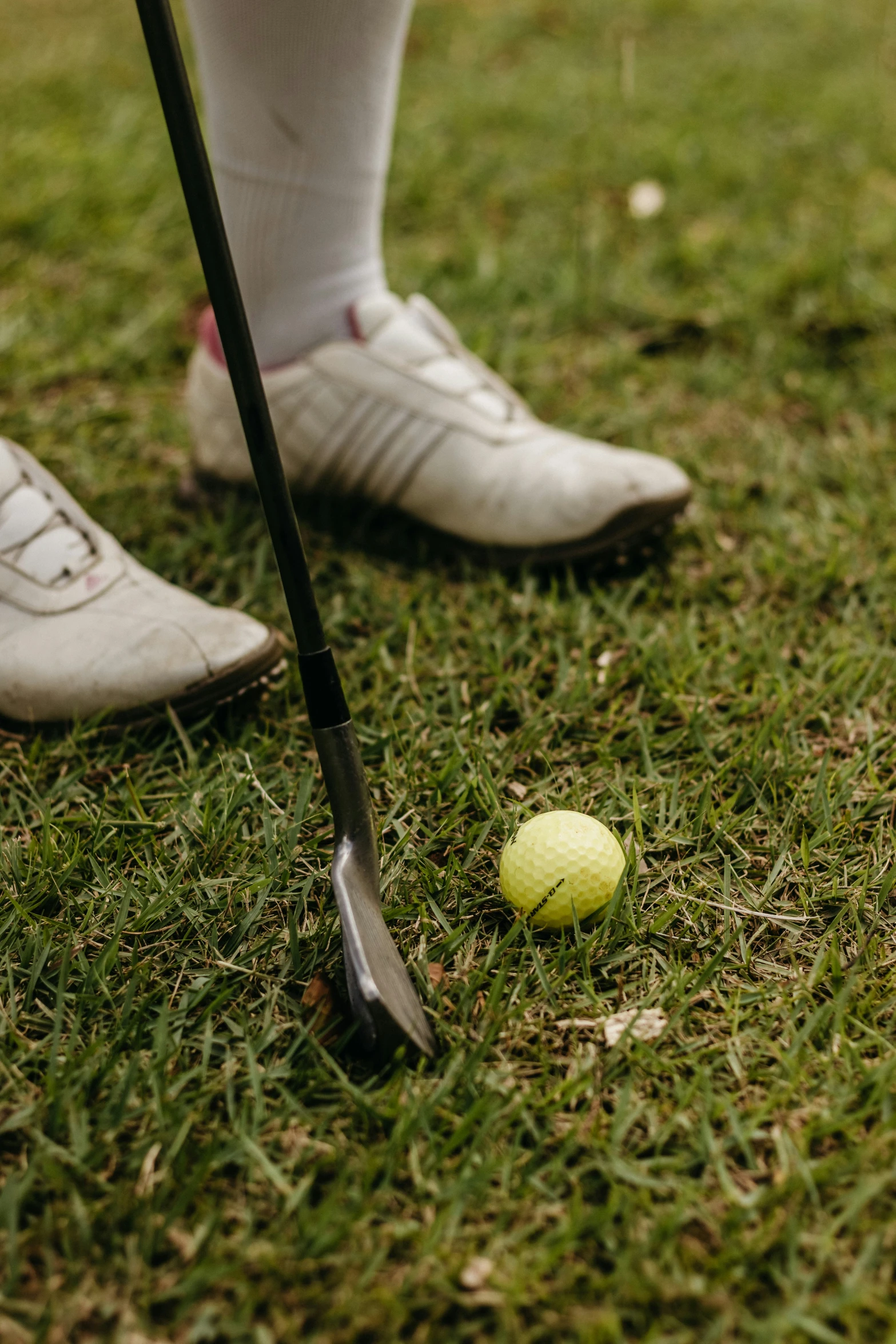 the legs and feet of a person with a golf ball and a club