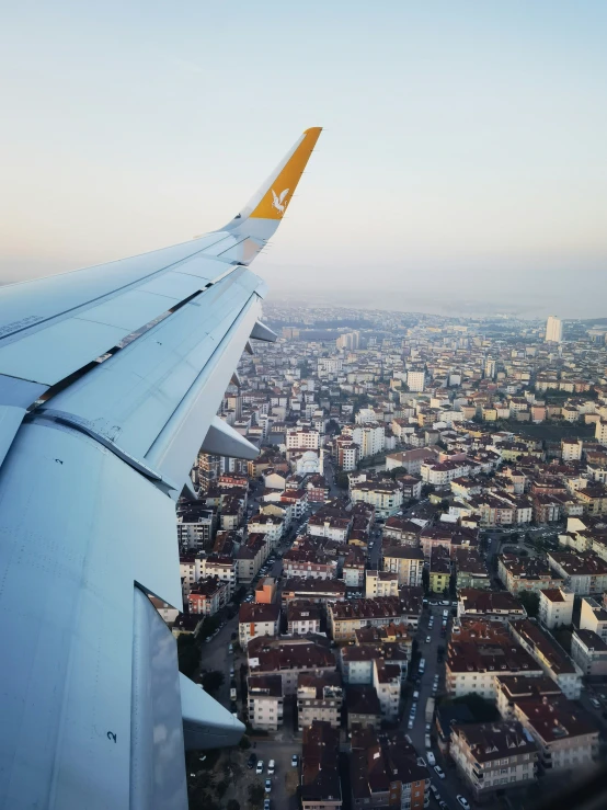 an airplane wing as it flies over a city