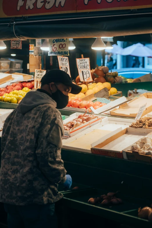 a man wearing a face mask standing in front of a fruit stand