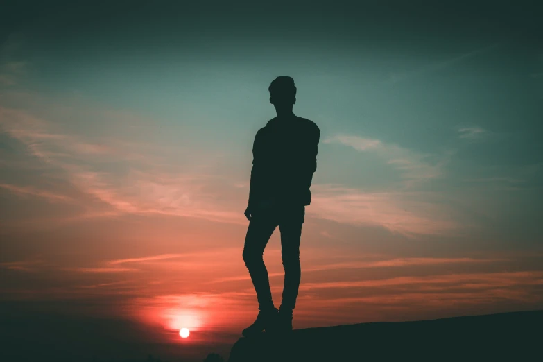 silhouetted man standing in the sunset on the beach