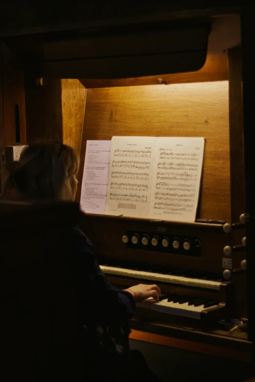 two people are playing an organ in a room with music sheets on it