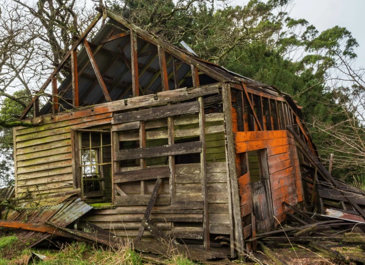 a dilapidated house with wood and rusted siding