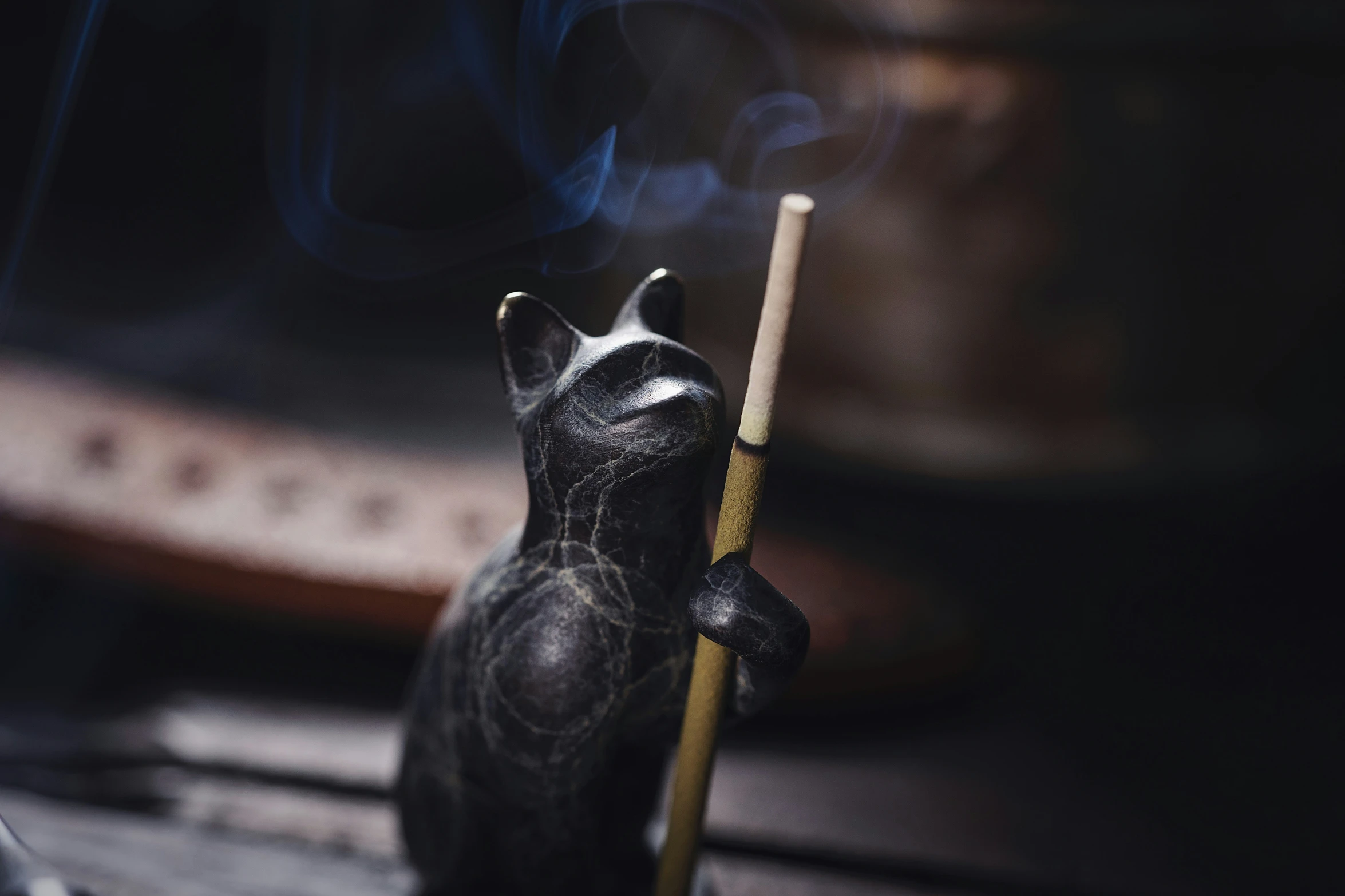 a cat statue holding a lit cigarette