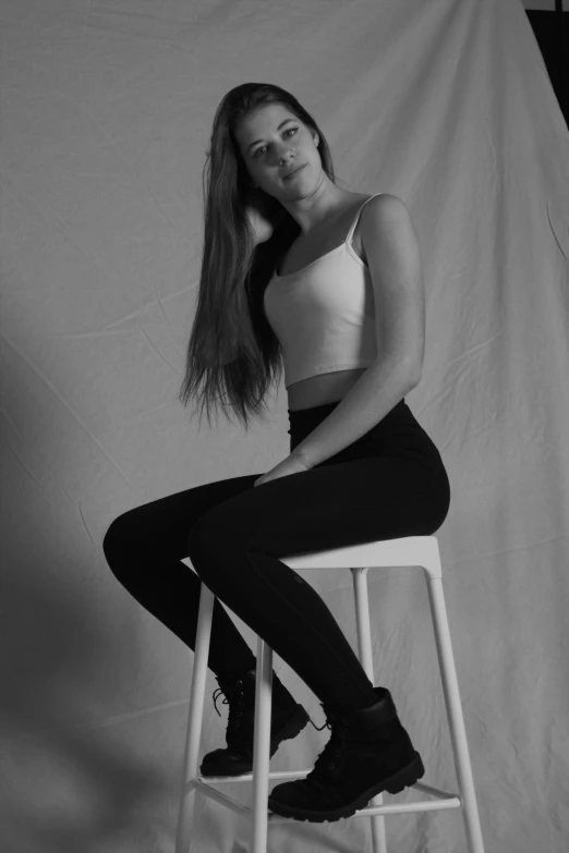 a beautiful young lady sitting on a stool posing for a po