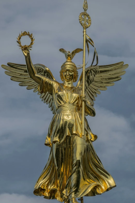 the gold statue is holding an ancient staff