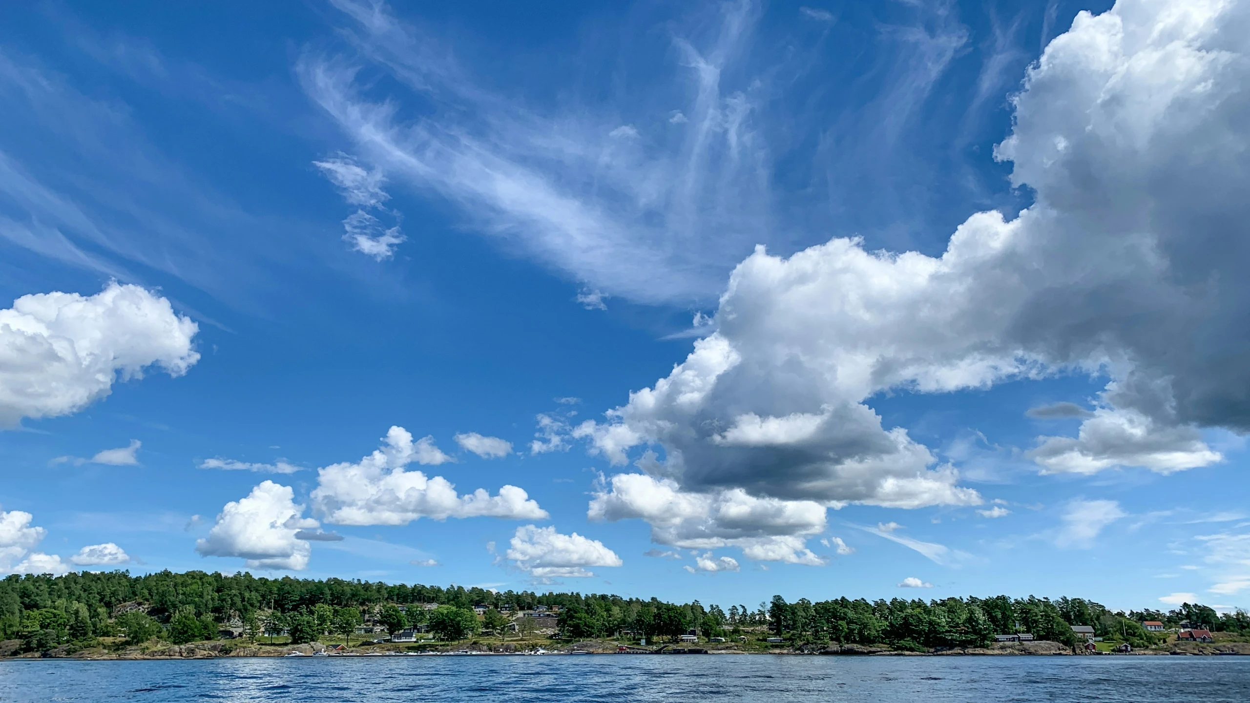 the water has clouds and trees on the shore