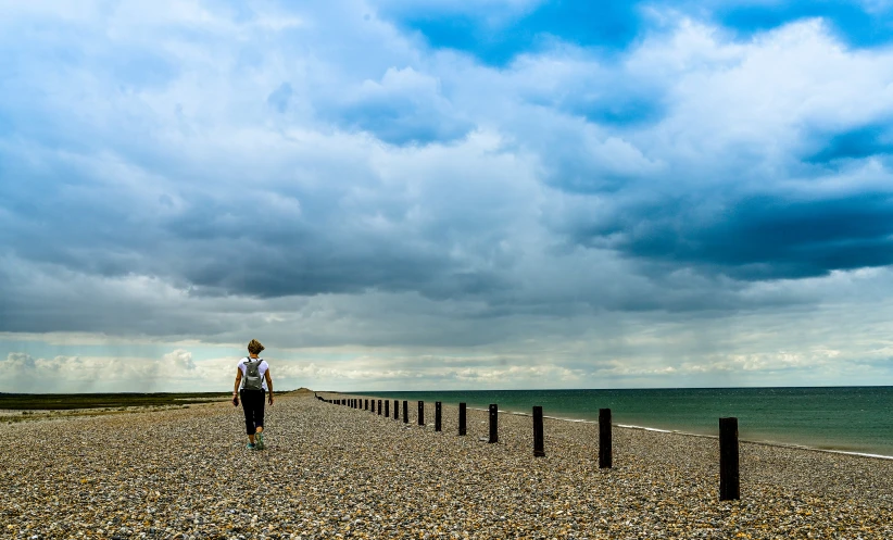 a person walking down the road toward the ocean