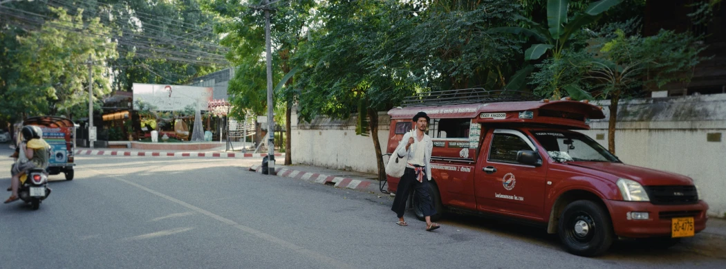 an orange truck parked next to a motorcycle in the middle of a road