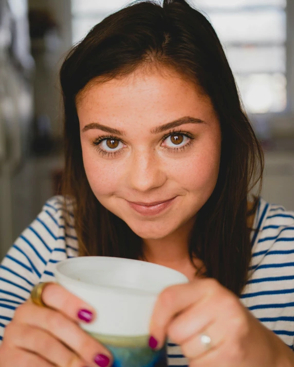 a woman sitting at a table holding a cup