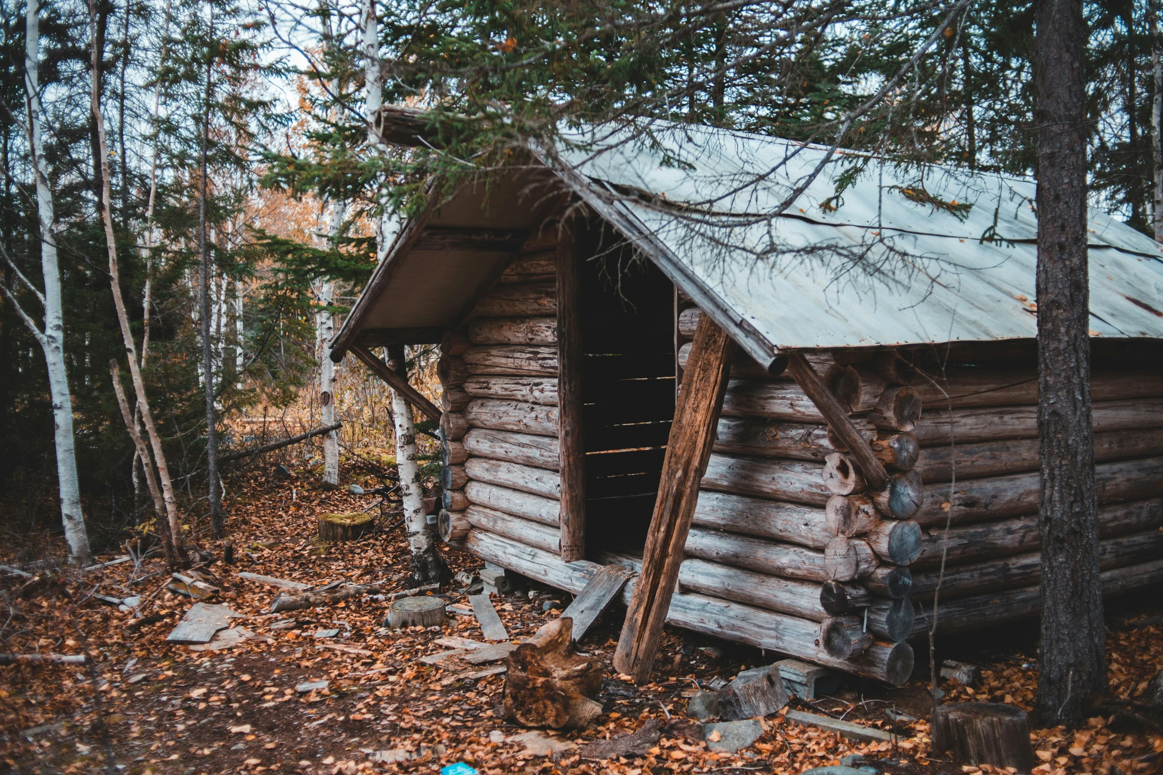 a log cabin with a roof made of wood and broken down windows