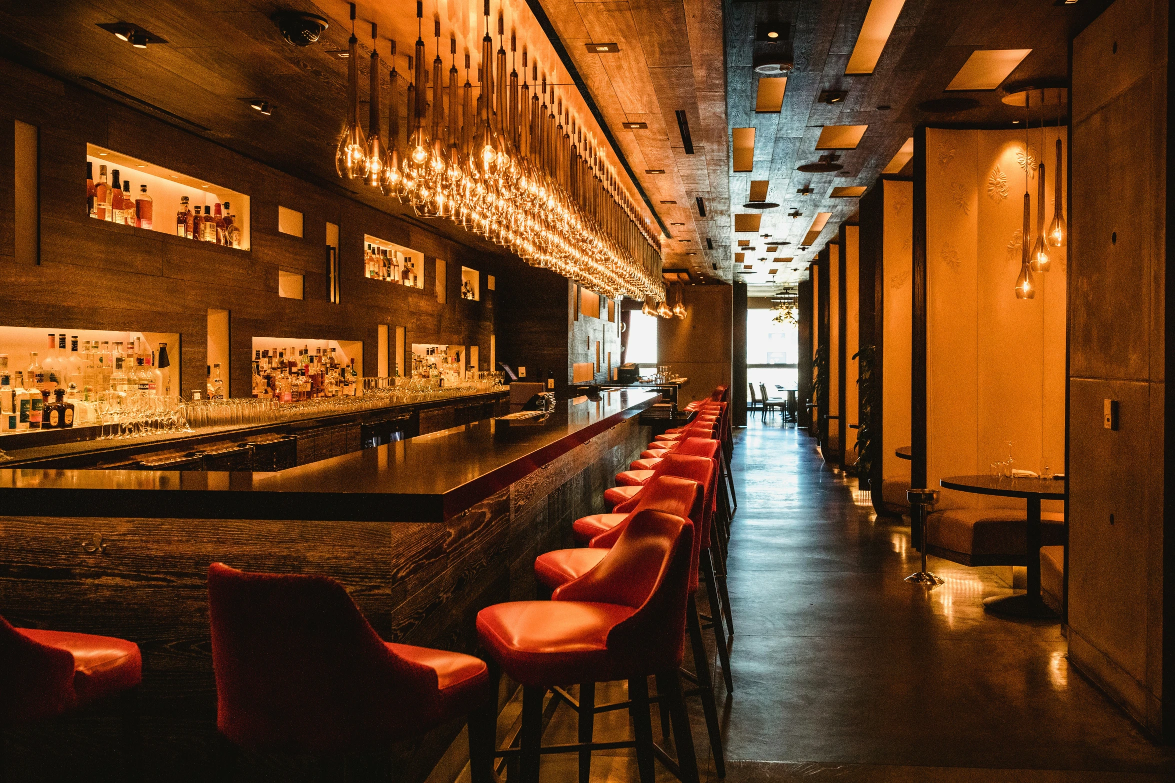 a dimly lit bar with a row of red seats