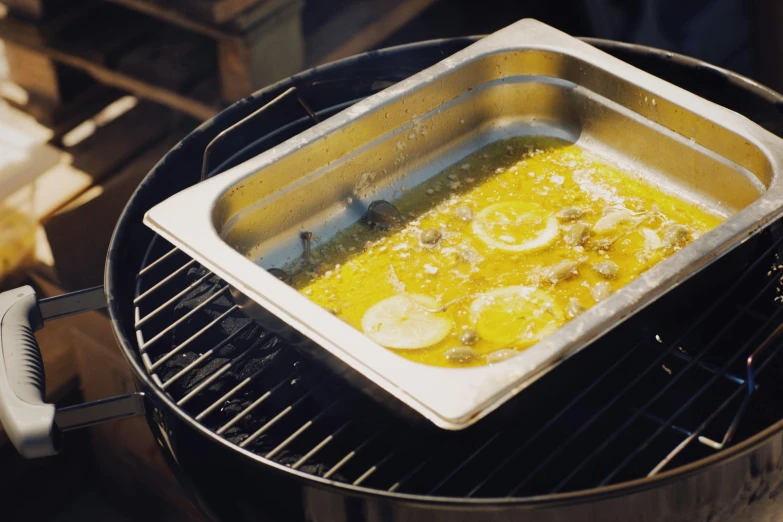 a casserole with lemons and onions cooking on an electric grill