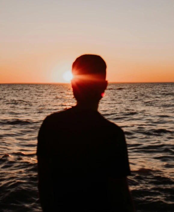 a man looks down at the ocean from an approaching ship