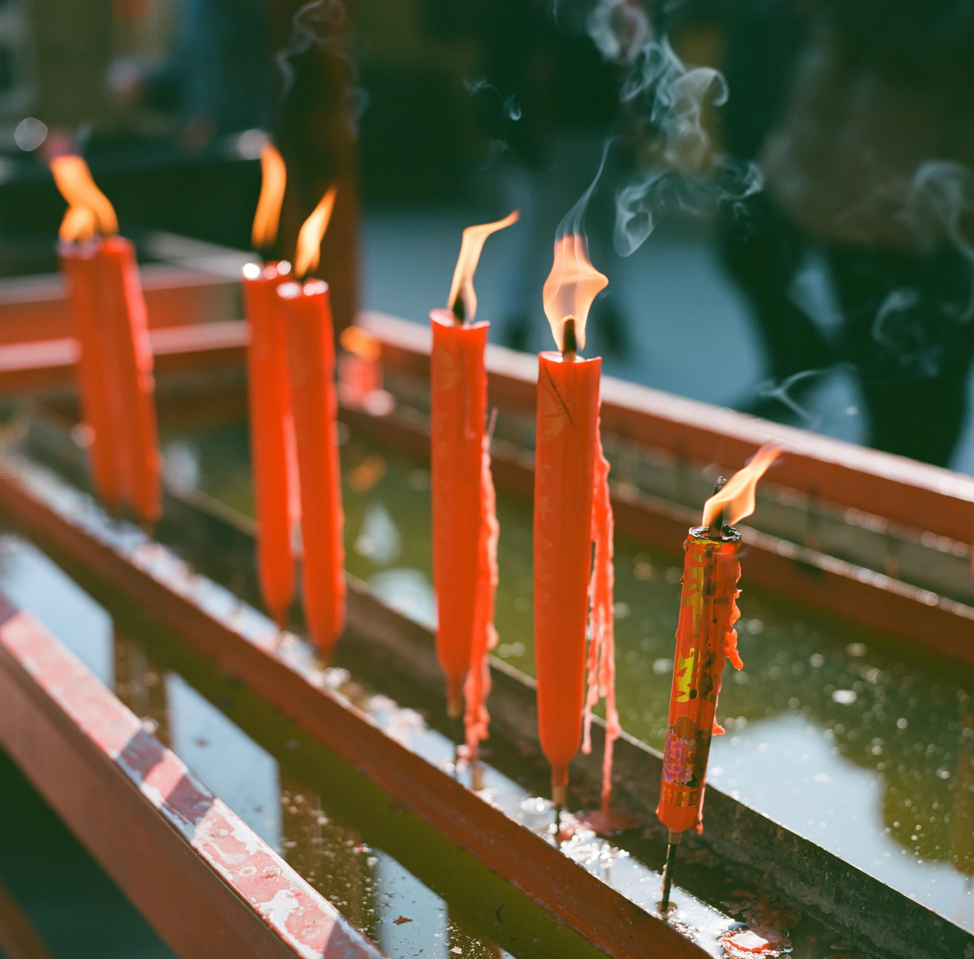 several lit orange candles sit on a bench in a row