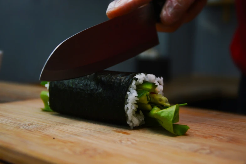 the person is preparing to cut up a sushi roll