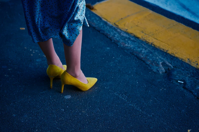 woman in blue dress and yellow shoes walking down street