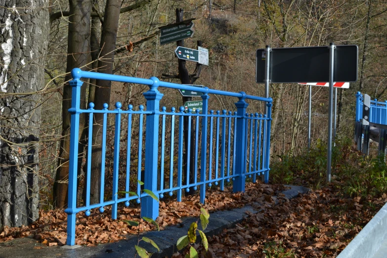 a blue gate is near a tree and the street sign