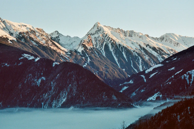a snowy mountain range with lake in foreground