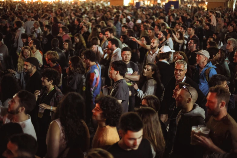 large crowd of people at an event, many of them are having drinks