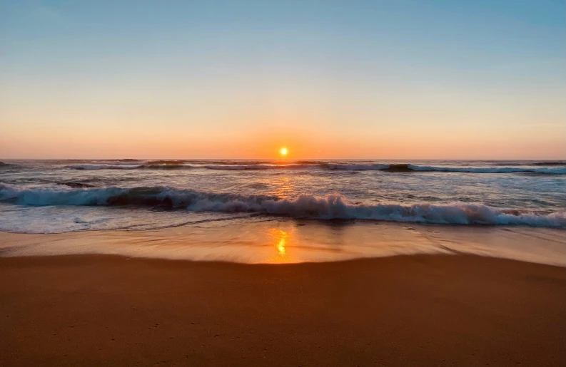 there is a sandy beach with waves coming in to the shore