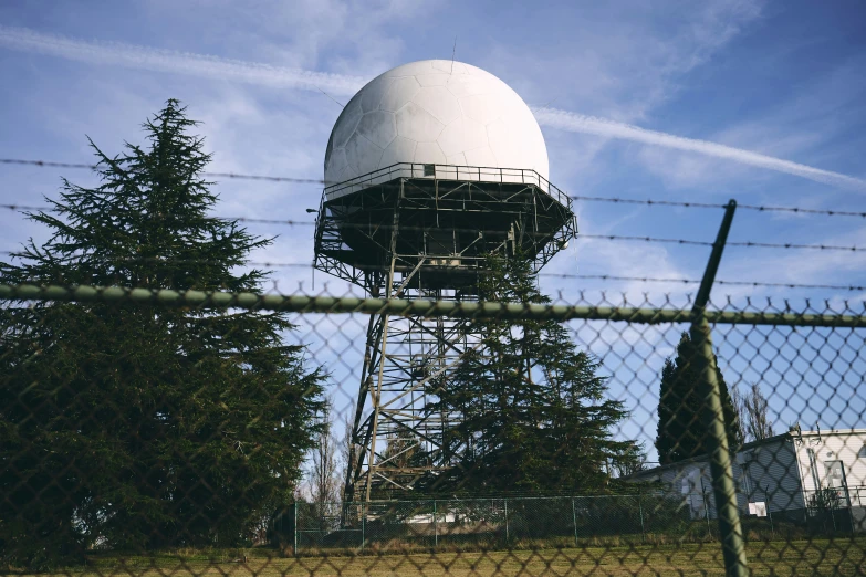 a tower with trees in the background near a fence