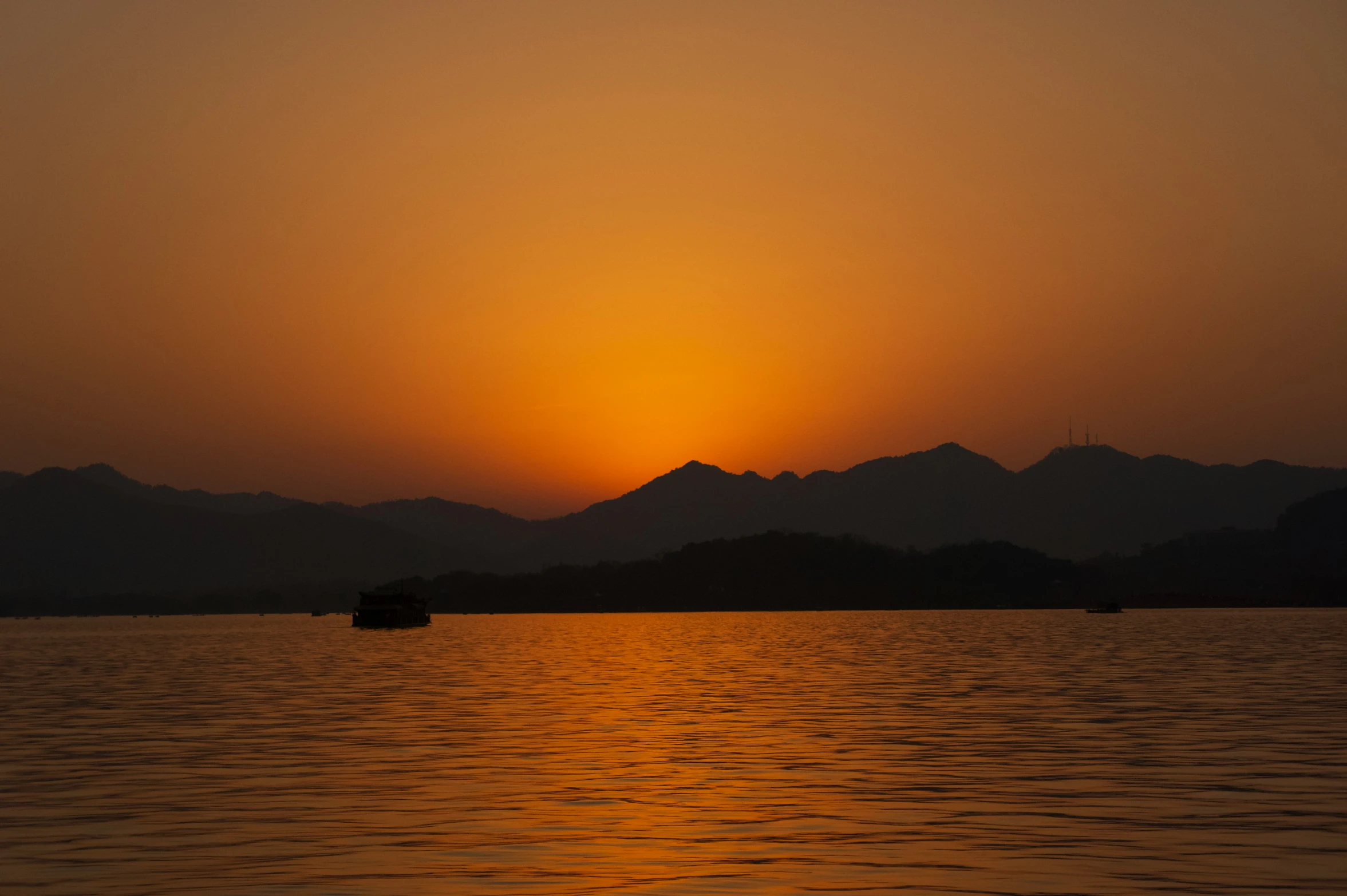 a beautiful sunset with the sun rising over mountains over the water