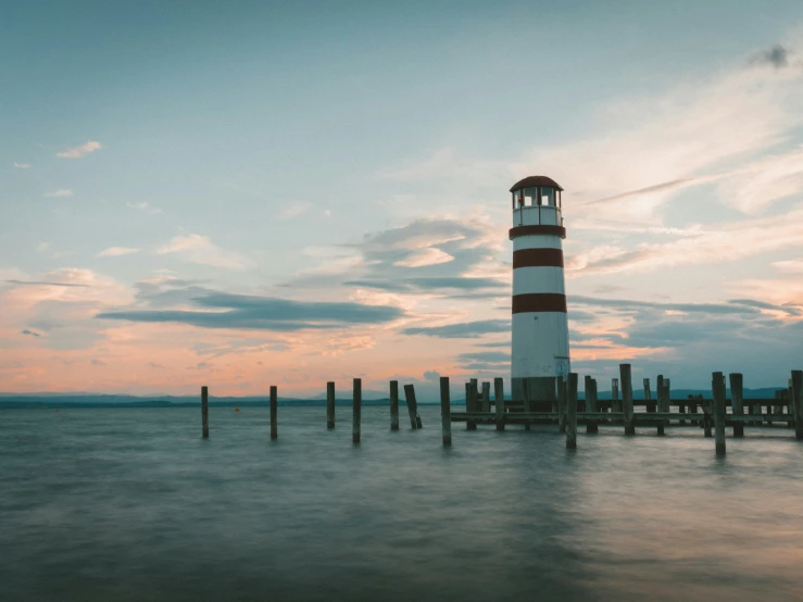 a white and red lighthouse sitting over a body of water