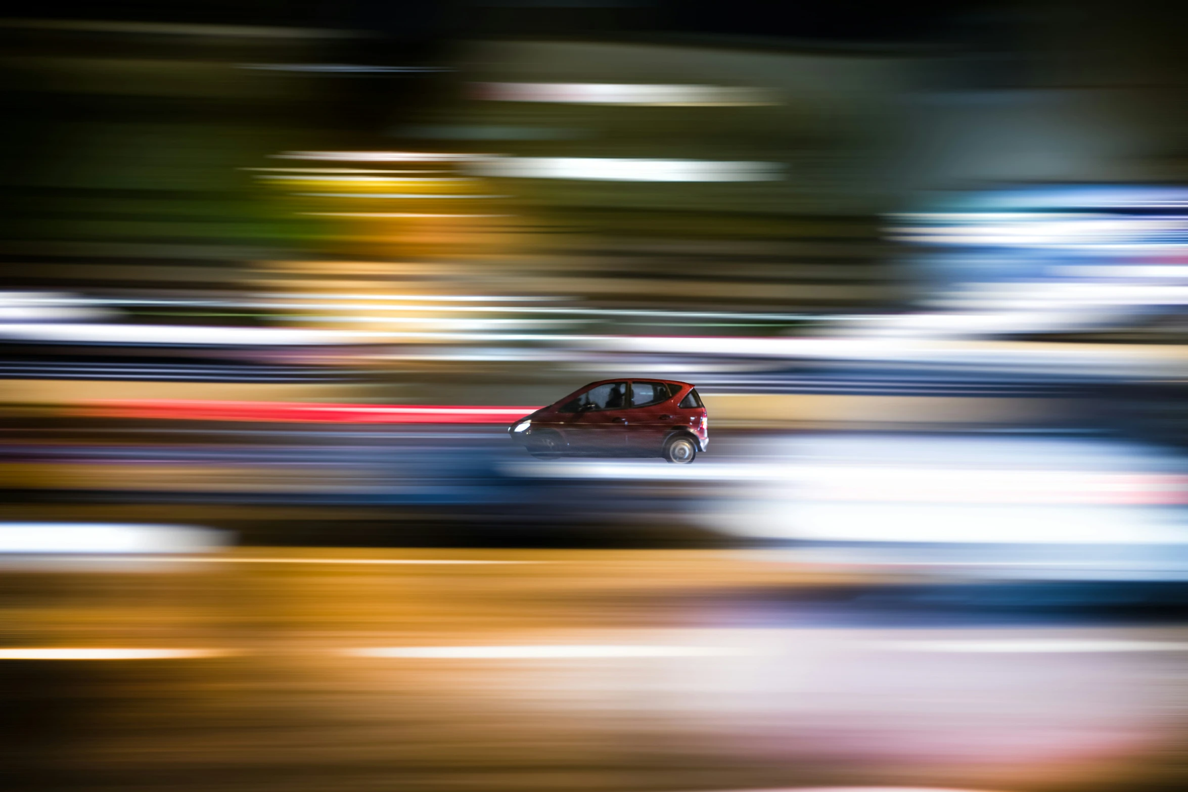 blurred pograph of a red car moving along the highway