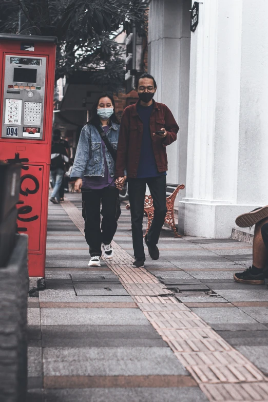 three men walking down a street with a red phone booth behind them