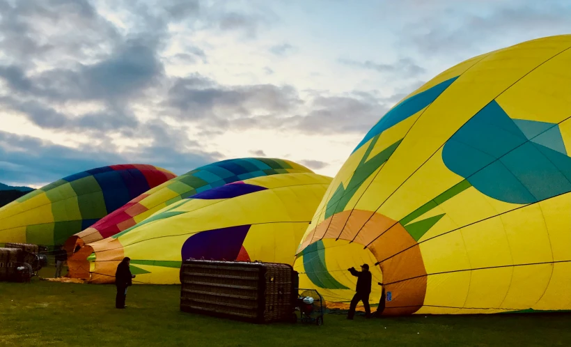 several large colorful balloons on a field in the sunset