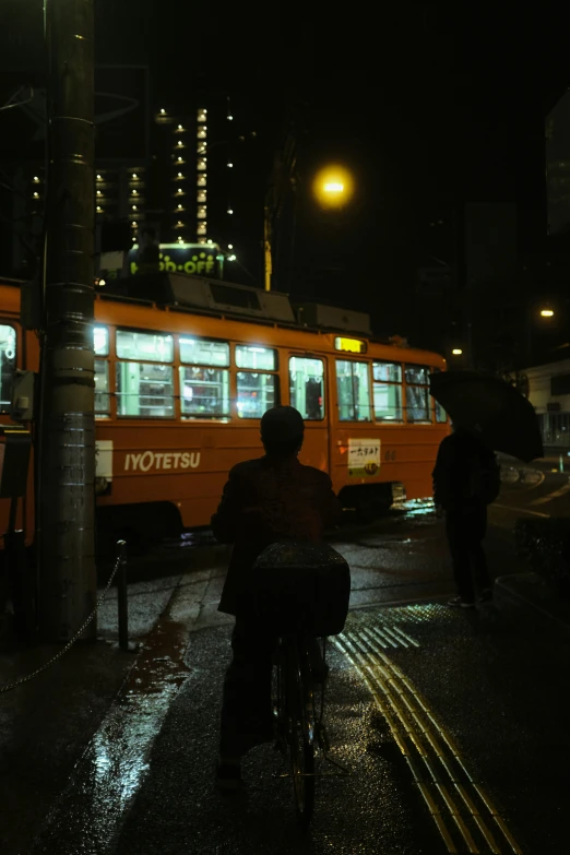 a person riding a bicycle in the rain in front of a train