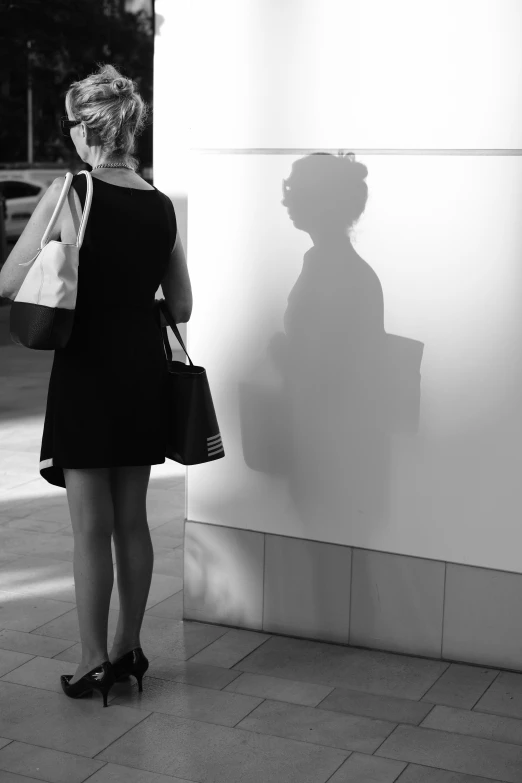 a woman in a black dress and heels standing next to a white building