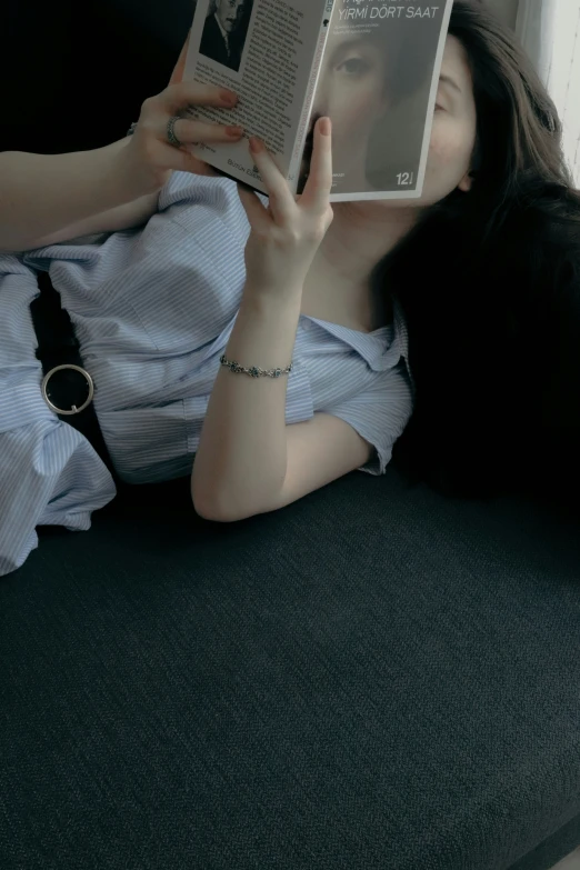 woman laying on the couch holding up some books