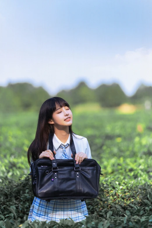 girl carrying bag in grassy field with cloudy sky