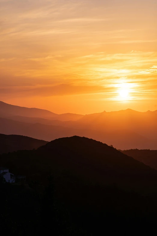 a bright sun setting over some mountains and hills