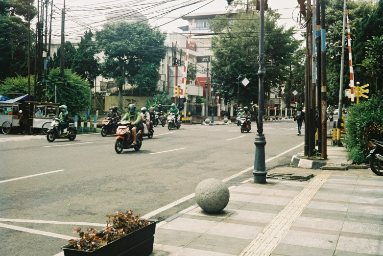 motorcycle riders pass by on an intersection with street signs and telephone poles